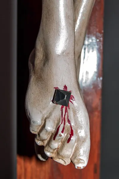 Nahaufnahme der angenagelten Füße einer Kruzifixfigur, Blut läuft aus der Nagelwunde