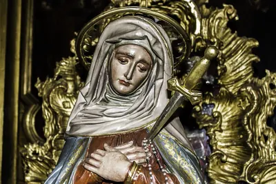 Farbige Marienfigur mit Schleier und Heiligenschein, ein Schwert durchbohrt ihre Brust