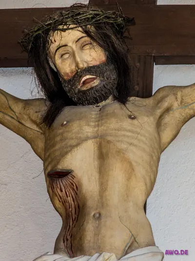 Lebensgroße Kruzifixfigur mit Echthaar und Dornenkrone, aus der Seitenwunde läuft Blut über den Bauch