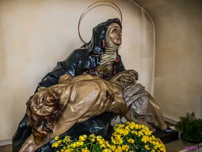 Große Pietà: Maria hält den Leichnam Jesu auf dem Schoß, davor gelbe Blumen
