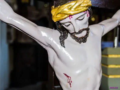 Weiß gefasste Kruzifixfigur mit goldener Dornenkrone, aus Stirn und Brust tropft Blut