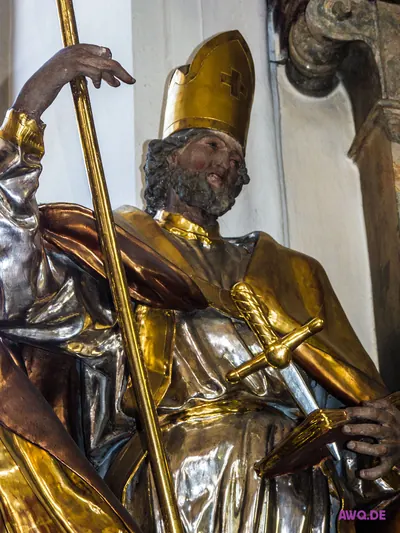 Vergoldete Bischofsfigur mit Mitra und Stab, ein Schwert steckt in ihrer Brust
