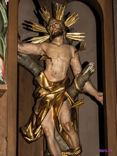 Christusfigur an einem Astkreuz mit goldenem Strahlenkranz, Blut läuft aus der Seitenwunde