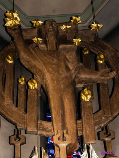 Große moderne Holzskulptur eines Christus mit ausgebreiteten Armen, umgeben von Kerzen mit vergoldeten Flammen