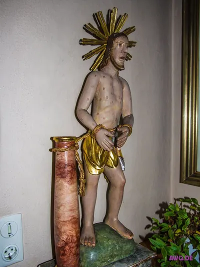 Sebastiansfigur mit Wundmalen, an eine Marmorsäule gefesselt, daneben eine Steckdose