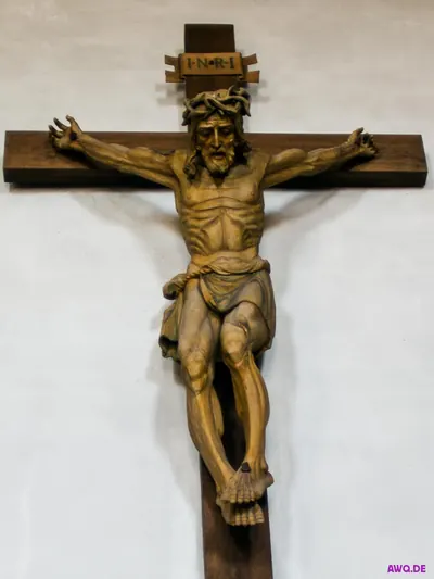 Großes Holzkruzifix mit Dornenkrone und INRI-Tafel an weißer Wand