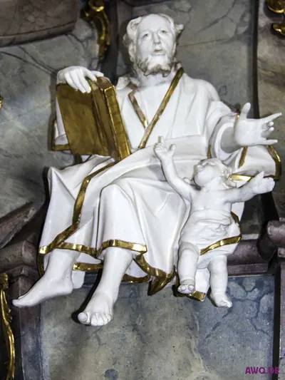 Weiß-goldene Evangelistenfigur mit aufgeschlagenem Buch, daneben ein Putto