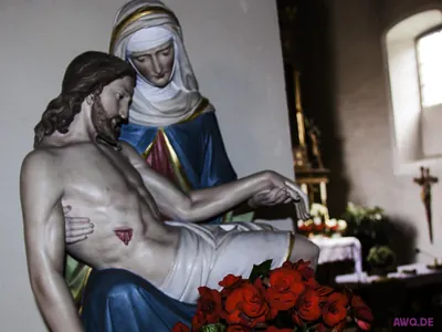 Pietà mit blauem Marienmantel, davor ein Strauß roter Rosen
