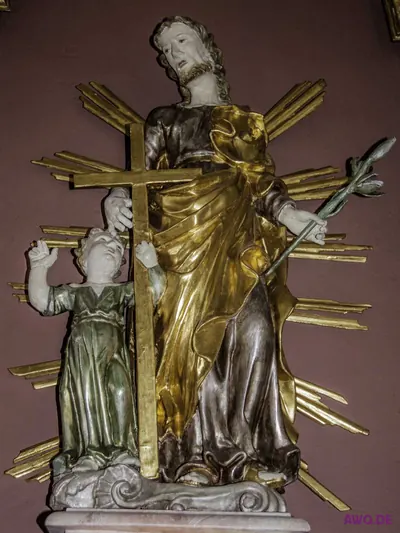 Vergoldete Heiligenfigur mit Kreuz und Palmzweig im Strahlenkranz, an sie geschmiegt ein Kind