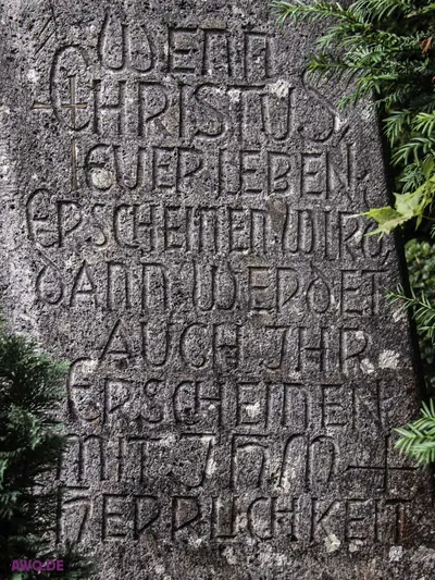 Verwitterte Steintafel mit eingemeißeltem Bibelvers über Christus und die Herrlichkeit