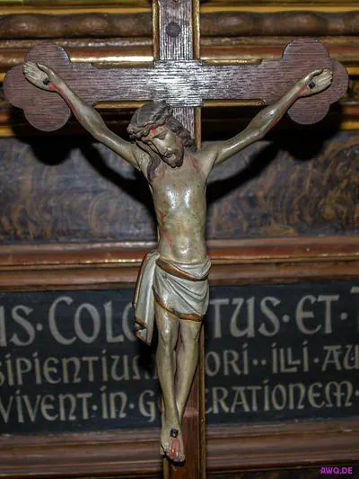 Kruzifix vor einer Tafel mit lateinischer Inschrift