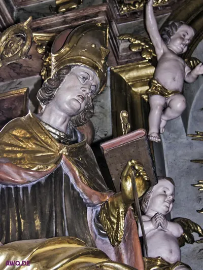 Bemalte Bischofsfigur mit Mitra und Buch, daneben schwebende Putten