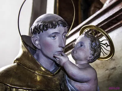 Nahaufnahme einer Antoniusfigur mit Heiligenschein, das Jesuskind greift ihm ans Kinn
