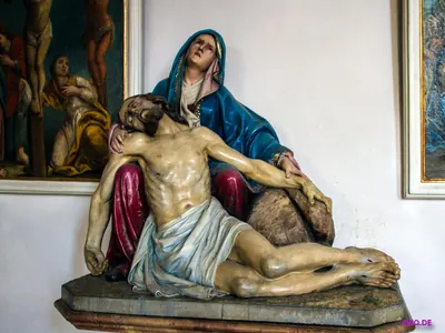 Farbige Pietà: Maria mit blauem Mantel hält den toten Jesus, dahinter ein Kreuzigungsgemälde