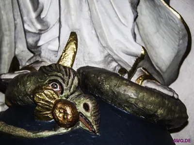 Detail einer Marienfigur: gehörnter Drachenkopf mit goldenem Apfel im Maul unter ihren Füßen