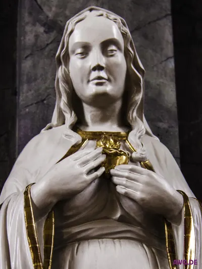 Weiße Marienfigur, die das vergoldete, von Rosen umgebene Herz an der Brust hält