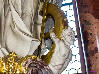 Altardetail: gehörnte Teufelsgestalt mit schmerzverzerrtem Gesicht, auf ein goldenes, mit Nägeln besetztes Rad gebunden – Darstellung einer Räderung