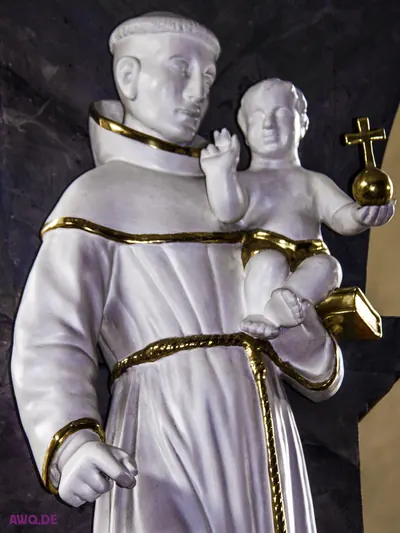 Weiße Figur des heiligen Antonius mit dem Jesuskind, das eine Kreuzkugel hält