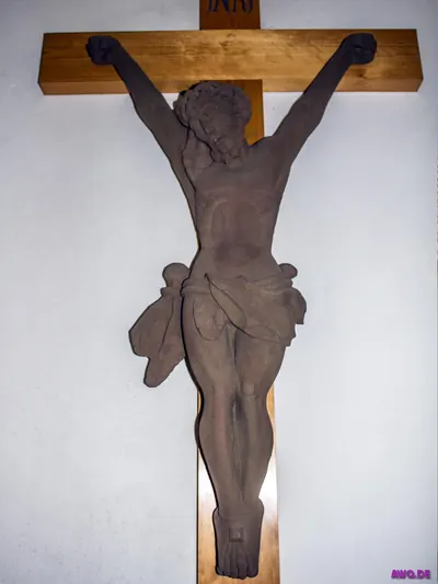 Modernes Kruzifix aus rostbraunem Metall an einem hellen Holzkreuz
