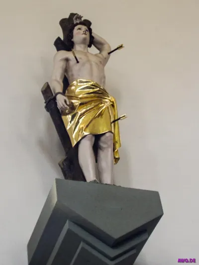 Sebastiansfigur mit goldenem Tuch und zwei Pfeilen im Körper auf einer grauen Konsole
