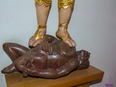 Detail einer Michaelsfigur: die Füße drücken eine am Boden liegende Teufelsgestalt auf den Sockel