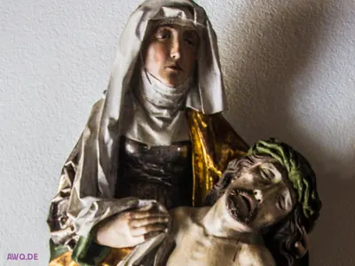 Nahaufnahme einer Pietà: Maria mit weißem Schleier, der Kopf Jesu mit grüner Dornenkrone und offenem Mund