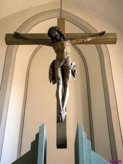Großes Holzkruzifix mit expressiver Christusfigur über einem blauen Altar