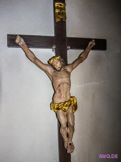 Kruzifix mit goldenem Lendentuch und blutenden Wunden an dunklem Holzkreuz