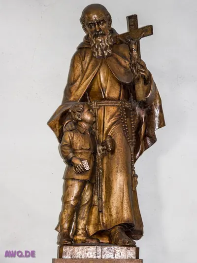 Holzfigur eines Ordensmannes mit Kruzifix und Rosenkranz, an ihn gelehnt ein Kind