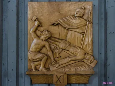 Holzrelief der XI. Kreuzwegstation: ein Mann schlägt den Nagel durch die Hand des liegenden Jesus
