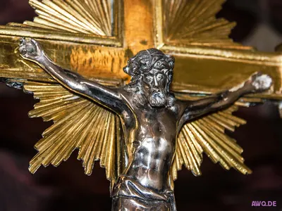 Silberne Christusfigur vor einem vergoldeten Strahlenkreuz