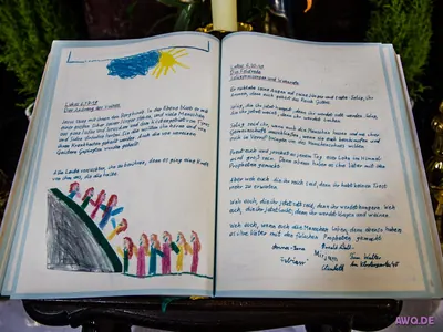 Aufgeschlagenes Buch mit der handschriftlich abgeschriebenen Feldrede aus Lukas 6, Kinderzeichnungen und Unterschriften