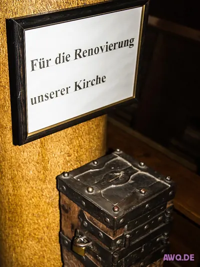 Eisenbeschlagener Opferstock unter dem Schild „Für die Renovierung unserer Kirche“