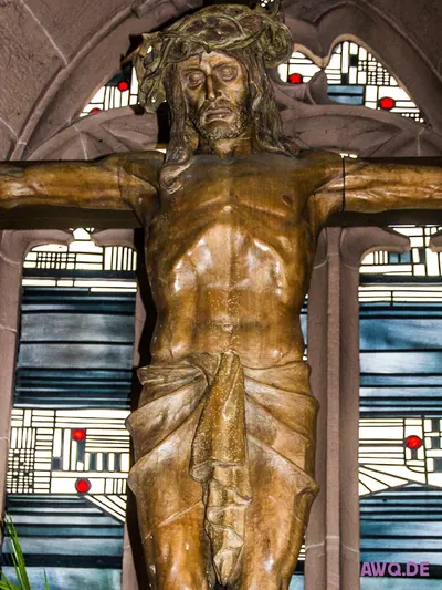 Nahaufnahme der Christusfigur mit Dornenkrone vor blauen Kirchenfenstern